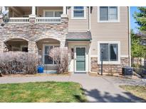 Inviting condo exterior with stone accents, manicured lawn, and a welcoming green front door at 9390 W Chatfield Pl # 108, Littleton, CO 80128