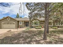 Inviting front exterior of a single-story home with mature landscaping and an attached two car garage at 19475 Stag Ln, Monument, CO 80132