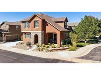 Charming two-story home with a stone archway, beautiful landscaping, and a cozy covered front porch at 10654 Ashfield St, Highlands Ranch, CO 80126