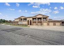 Inviting townhome with a beige exterior, stone accents, covered balconies, and multiple attached garages at 7131 S Wenatchee Way # F, Aurora, CO 80016