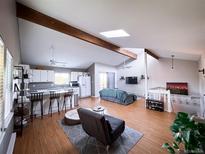 Bright living room with hardwood floors, skylight, white walls, and vaulted ceiling at 30819 Hilltop Dr, Evergreen, CO 80439