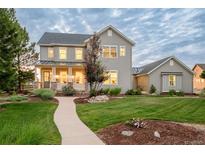 Charming two-story home featuring a landscaped yard, covered porch, and neutral gray siding under a cloudy sky at 5397 Lenox Ct, Castle Rock, CO 80104