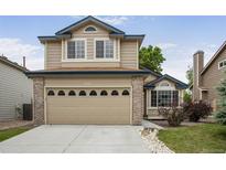 Charming two-story home featuring tan siding, brick accents, and an attached two car garage at 9669 Jellison Way, Broomfield, CO 80021