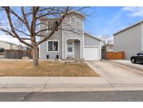 Charming gray two-story home featuring a well-manicured front yard, attached garage, and inviting entryway at 1212 Magpie Ave, Brighton, CO 80601