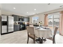 Modern kitchen features stainless steel appliances, sleek countertops, and a dining area with sliding glass door to outside at 1212 Magpie Ave, Brighton, CO 80601