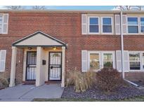 Charming red brick townhouse featuring a covered front porch and well-maintained landscaping at 2805 Jasmine St, Denver, CO 80207