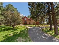 Charming front exterior with brick accents, mature trees, and a long driveway at 465 Indian Way, Monument, CO 80132