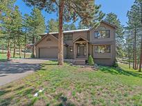 Two-story home featuring a well-manicured lawn and a welcoming covered front entry in a wooded, landscaped setting at 4228 Scenic Village Dr, Evergreen, CO 80439
