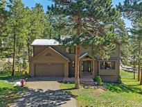 Charming home featuring a two-car garage and a welcoming covered front entry in a wooded, landscaped setting at 4228 Scenic Village Dr, Evergreen, CO 80439