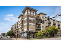 Multi-story brick and stucco condo building with balconies and commercial space, plus streetscape at 1441 Central St # 203, Denver, CO 80211