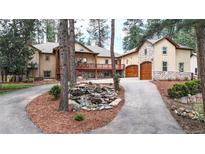 Stunning two-story home with stone accents, a water feature, and a beautiful, wooded landscape at 4456 Mohawk Dr, Larkspur, CO 80118