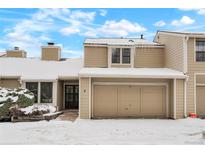 Tan two-story townhome with attached garage and snowy landscaping at 1011 Pierce St # 5, Lakewood, CO 80214