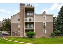Multi-story condo with balconies, stone chimney, neutral siding, and well-maintained lawn at 4896 S Dudley St # 8-11, Littleton, CO 80123