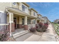 Charming townhome with a covered front porch, brick accents, and landscaped front yard at 16051 E Geddes Dr # 66, Aurora, CO 80016