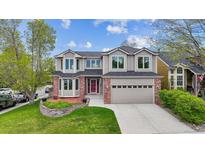 Charming two-story home featuring a well-manicured lawn and a two-car garage with red brick and a red door at 5282 Devon Ave, Castle Rock, CO 80104