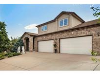 Elegant brick home featuring a two-car garage, well-maintained landscaping, and classic architectural details at 2595 S Harlan Ct, Lakewood, CO 80227