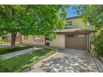 Inviting exterior featuring a charming brick facade, lush lawn, mature trees, and a convenient attached two car garage at 2518 S Patton Ct, Denver, CO 80219