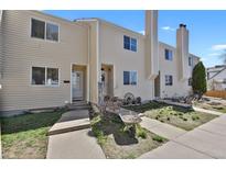 Charming townhome exterior with a cozy entrance and well-maintained beige siding under a clear blue sky at 1287 Benton St, Lakewood, CO 80214