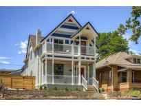 Charming two-story home featuring a double-decker porch, a red front door, and stone wall landscaping at 2021 Eliot St, Denver, CO 80211