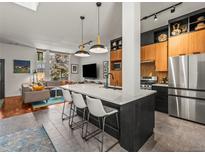 A modern kitchen features a large island with seating, sleek countertops, and stainless steel appliances at 3133 Blake St # 3, Denver, CO 80205
