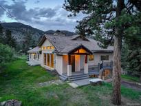 Charming home features a tile roof, stucco exterior, and covered front porch, nestled amongst the trees at 96 Carolyn Rd, Evergreen, CO 80439