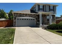 Charming two-story home featuring stone accents, attached two-car garage, and a well-manicured lawn at 24748 E Layton Pl, Aurora, CO 80016