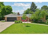 Charming brick home with a well-manicured lawn, lush landscaping, and inviting front porch with red chairs at 721 Park Ln, Lakewood, CO 80214
