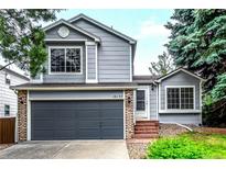 Charming two-story home with gray siding, brick accents, and a well-manicured front lawn with lovely trees at 10172 Woodrose Ln, Highlands Ranch, CO 80129