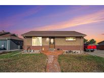 Charming single-story brick home featuring a well-maintained front lawn, pathway, and new roof at 7066 Jennie Dr, Denver, CO 80221