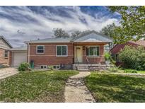 Charming brick home featuring a covered porch and well-maintained front yard with a walkway at 1334 Xavier St, Denver, CO 80204