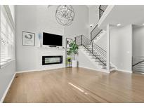 Spacious living room featuring a modern fireplace, wood floors and open staircase at 3026 S Waco Ct, Aurora, CO 80013