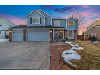 Charming two-story home with brick accents, large driveway and well-lit exterior at dusk at 1143 W 124Th Ct, Westminster, CO 80234