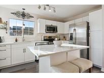 Bright kitchen featuring white cabinets, stainless steel appliances, and an island with seating at 23505 E Platte Dr # 8A, Aurora, CO 80016