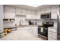Well-lit kitchen featuring white cabinets, subway tile backsplash, and stainless steel appliances at 14091 E Marina Dr # 612, Aurora, CO 80014