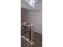 Hallway featuring new carpet, modern light fixture, closet, and white railing with dark spindles at 5319 Morning Glory Pl, Highlands Ranch, CO 80130