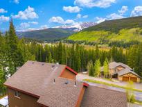 Breathtaking aerial view of a mountain home surrounded by lush trees and a backdrop of snow-capped mountains at 322 Davis Ct, Breckenridge, CO 80424