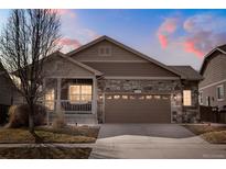 Charming single-Gathering home featuring a stone facade, covered porch, and two-car garage at 5172 Purple Mustard Ct, Brighton, CO 80601
