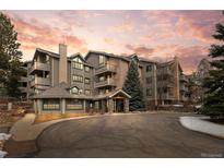 Inviting exterior of a multi-story condo building with stone accents and manicured landscaping against a colorful sunset at 31719 Rocky Village Dr # 317, Evergreen, CO 80439