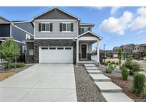 Charming two-story home with gray siding, stone accents, a two-car garage, and well-manicured landscaping at 27504 E 1St Pl, Aurora, CO 80018