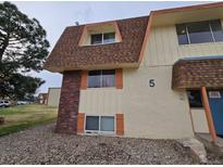 Multi-Gathering townhouse exterior with brown shingled roof, tan siding, brick, and rocks at 10211 Ura Ln # 5-206, Thornton, CO 80260