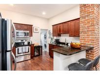 Updated kitchen with stainless steel appliances, wood cabinets, breakfast bar, and stacked washer/dryer at 3220 W 24Th Ave, Denver, CO 80211