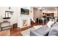 Open-concept living room features a decorative fireplace, hardwood floors, and exposed brick accent wall at 3220 W 24Th Ave, Denver, CO 80211
