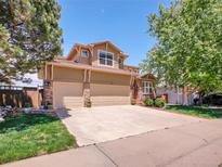 Charming two-story home featuring a large driveway and a well-maintained front yard with mature trees at 2485 Greensborough Cir, Highlands Ranch, CO 80129