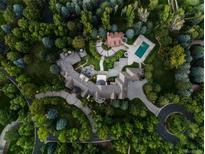 Stunning aerial view of estate featuring pool, lush landscaping, and winding driveway, showcasing the expansive property at 5 Mockingbird Ln, Cherry Hills Village, CO 80113