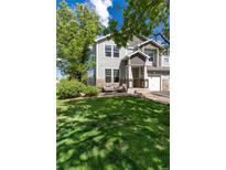 Charming two-story home with gray siding, stone accents, covered porch, and a lush green lawn at 4797 Flower St, Wheat Ridge, CO 80033