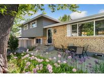 Charming home with a brick facade, complemented by lush landscaping and a cozy outdoor seating area at 1713 S Holland St, Lakewood, CO 80232