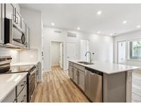 Modern kitchen features stainless appliances, quartz countertops, and an island with a sink at 485 Interlocken Blvd # 106, Broomfield, CO 80021