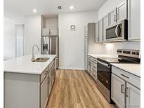 Bright kitchen features stainless steel appliances, gray cabinets, quartz countertops, and wood flooring at 485 Interlocken Blvd # 106, Broomfield, CO 80021