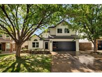 Charming two-story home featuring a modern black garage door, white brick, and lovely front-yard landscaping at 9371 Princeton Ln, Highlands Ranch, CO 80130