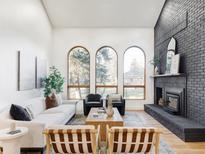 Bright living room featuring a painted brick fireplace and three large arched windows overlooking the front yard at 1 Winged Foot Way, Littleton, CO 80123